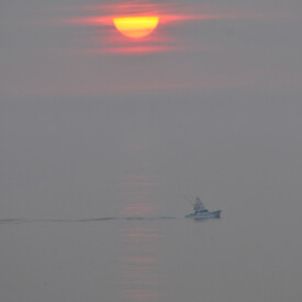 A calm sea with a one fishing boat at sunrise in Truro, MA