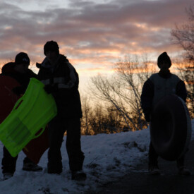 kids sledding at sunset in winter
